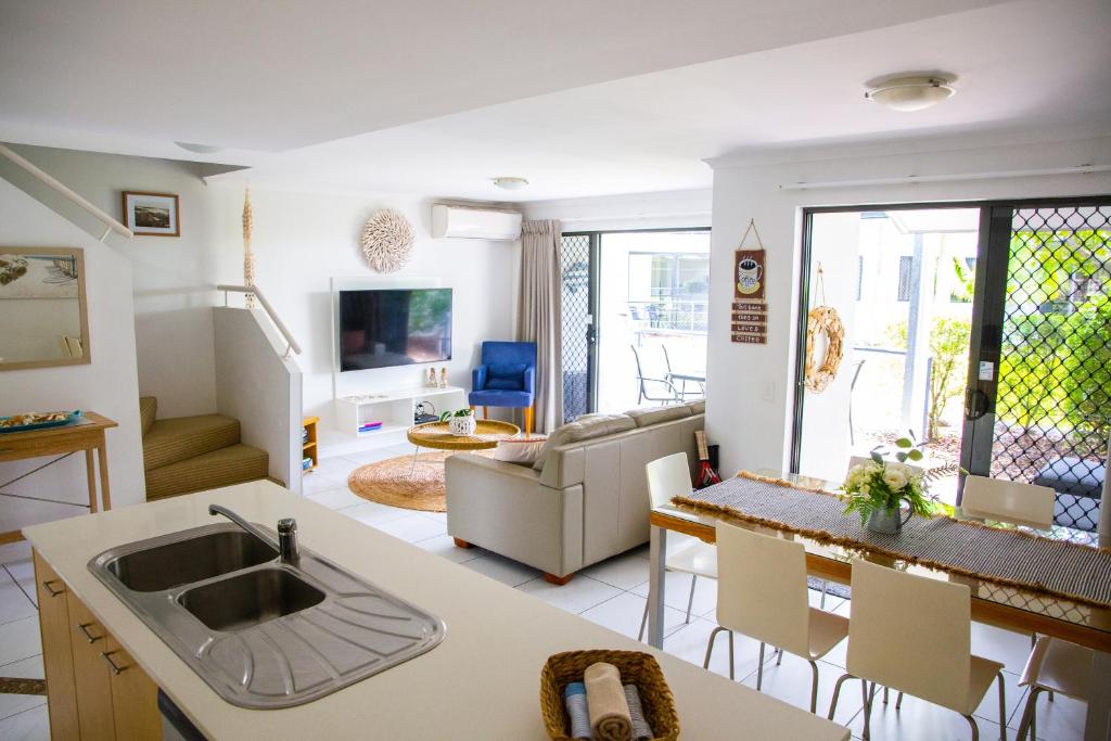 uma cozinha e sala de estar com um lavatório e uma mesa em Tropical Getaway in 2 Bedroom Unit in 4 star Resort em Noosaville