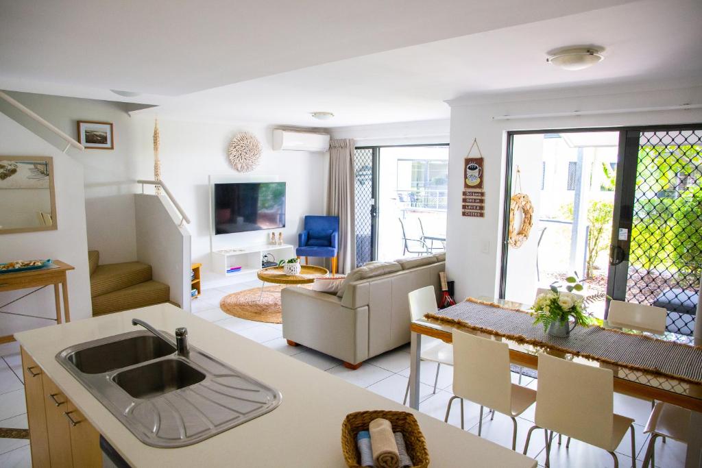 a kitchen and living room with a sink and a table at Tropical Getaway in 2 Bedroom Unit in 4 star Resort in Noosaville