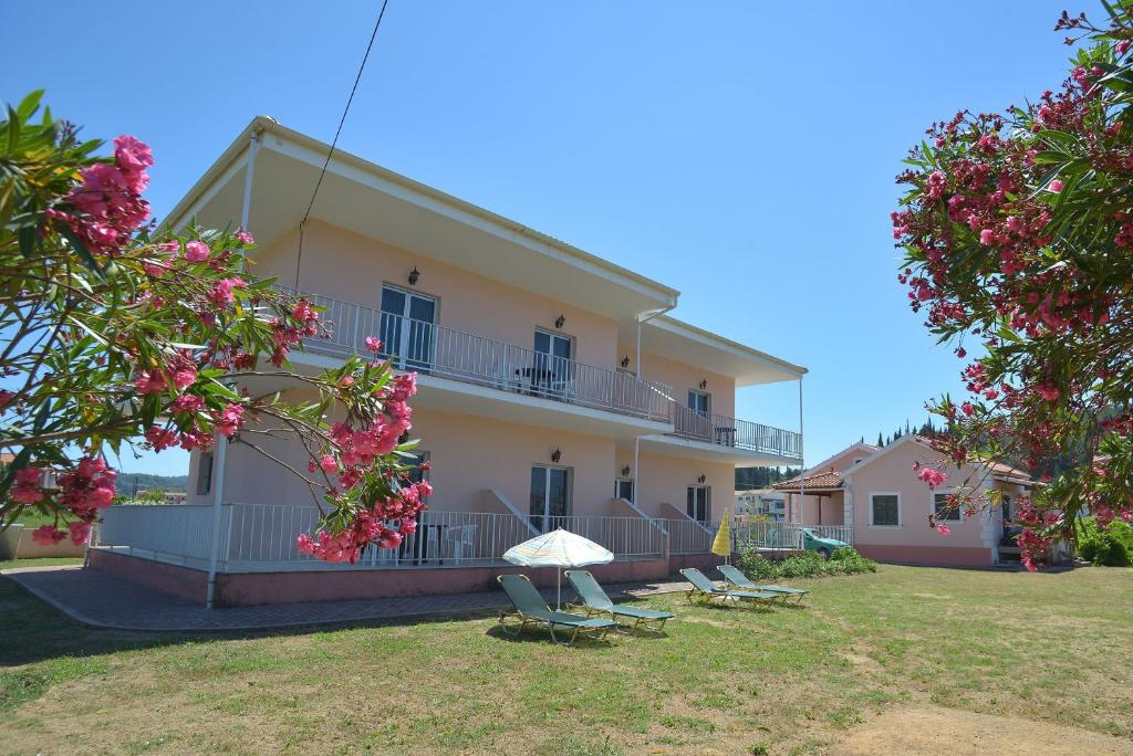 ein Gebäude mit zwei Stühlen und einem Gebäude mit Blumen in der Unterkunft Botzoris Apartments in Sidari