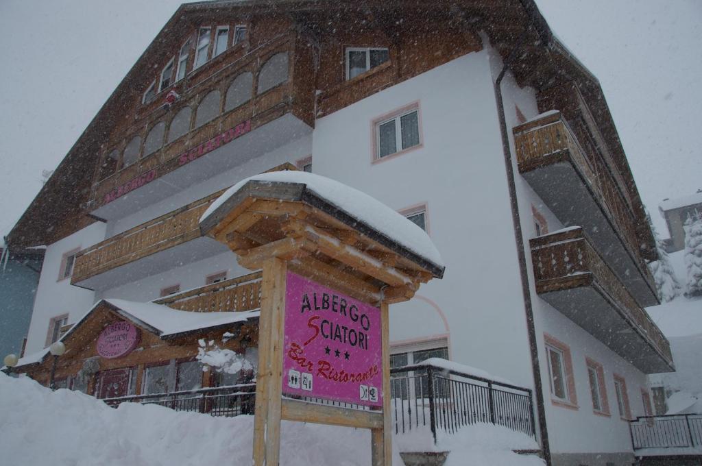 ein Schild im Schnee vor einem Gebäude in der Unterkunft Hotel Sciatori in Passo del Tonale