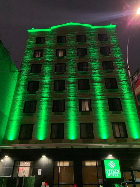 un edificio con luces verdes en el lateral. en Pitkin Hotel, en Brooklyn