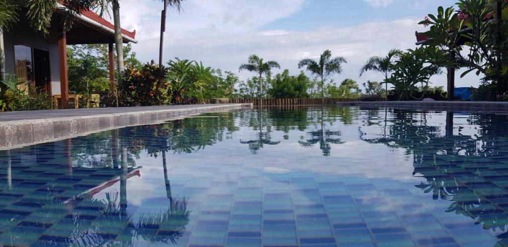 einen Pool in einem Resort mit Palmen in der Unterkunft Ombak Resort at Ekas , a luxury surf and kite surf destination in Ekas