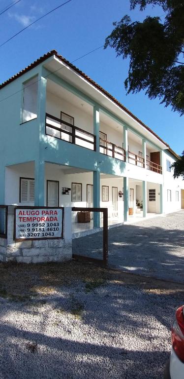 een wit gebouw met een hek ervoor bij Pousada Araçatuba in Imbituba