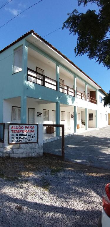 a white building with a fence in front of it at Pousada Araçatuba in Imbituba