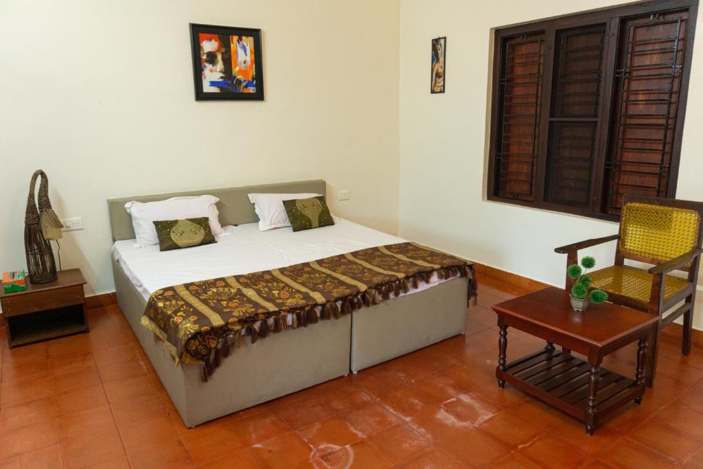 a bedroom with a bed and a chair and a table at CANALVIEW PRIVATE COTTAGE Azhikkal Ayiram Thengu in Panmana