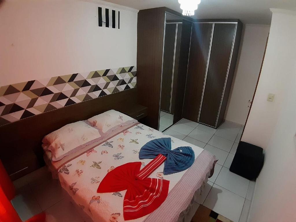 ein kleines Schlafzimmer mit einem Bett mit roten und blauen Schleifen in der Unterkunft Apartamento no Bessa in João Pessoa