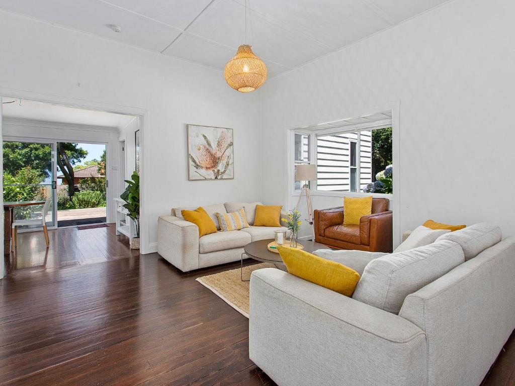 uma sala de estar com mobiliário branco e almofadas amarelas em Merioola Retreat em Gerringong