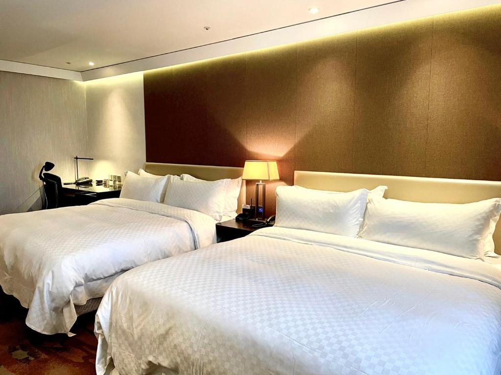 two beds in a hotel room with white pillows at The Tango Taichung in Taichung
