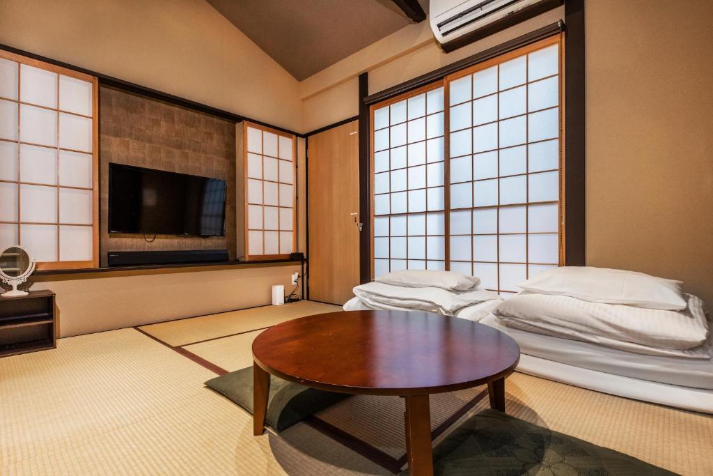 a room with two beds and a table in it at Shiki Homes SEN in Kyoto