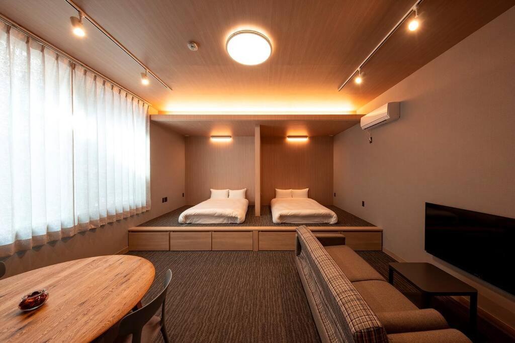 Habitación con 2 camas, mesa y TV. en White Crystal RoomA, en Fukuoka