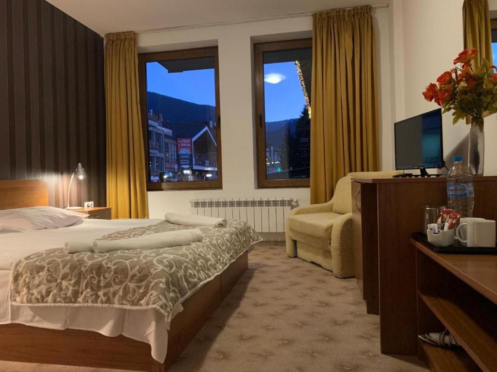 een hotelkamer met een bed, een stoel en ramen bij Room in Guest room - Apartment StayInn Granat in Bansko - next to Gondola Lift, perfect for 3 guests in Bansko