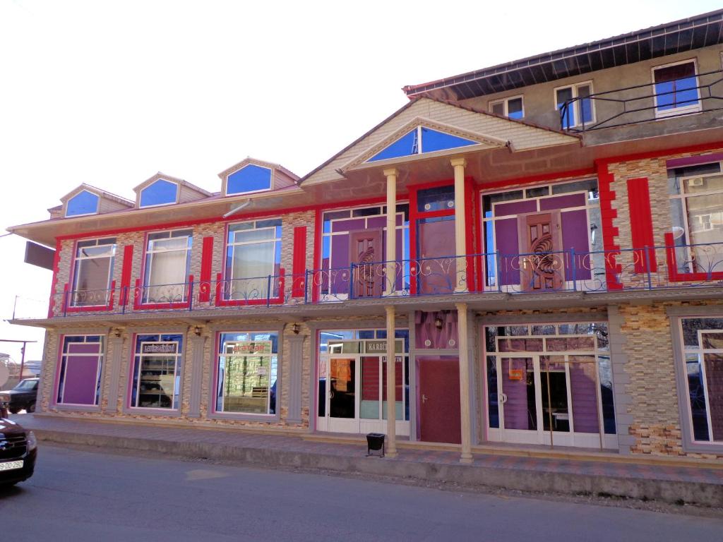 um edifício com janelas e varandas numa rua em Tubram S Ailəvi Qonaq Evi em Sheki