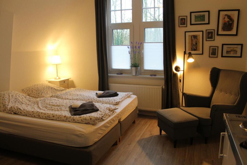 a bedroom with a bed and a chair and a window at Apartment am Wall in Emden
