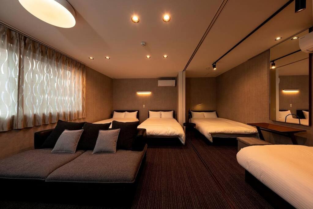 una camera d'albergo con due letti e un divano di White Crystal RoomB a Fukuoka