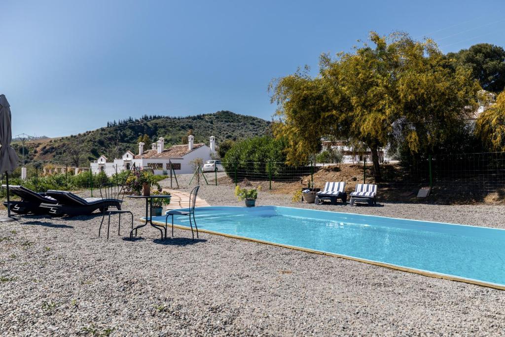 una piscina en un patio con sillas y una casa en Rosas Cantares: Casa Maurus. en Pizarra