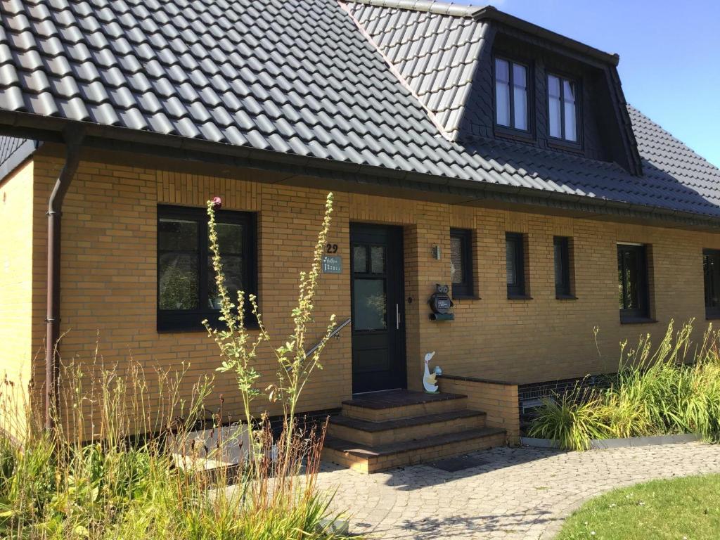 una casa amarilla con un gato sentado en el porche delantero en Ferienhaus-Selker-Noorblick-mit-Thermomix, en Selk