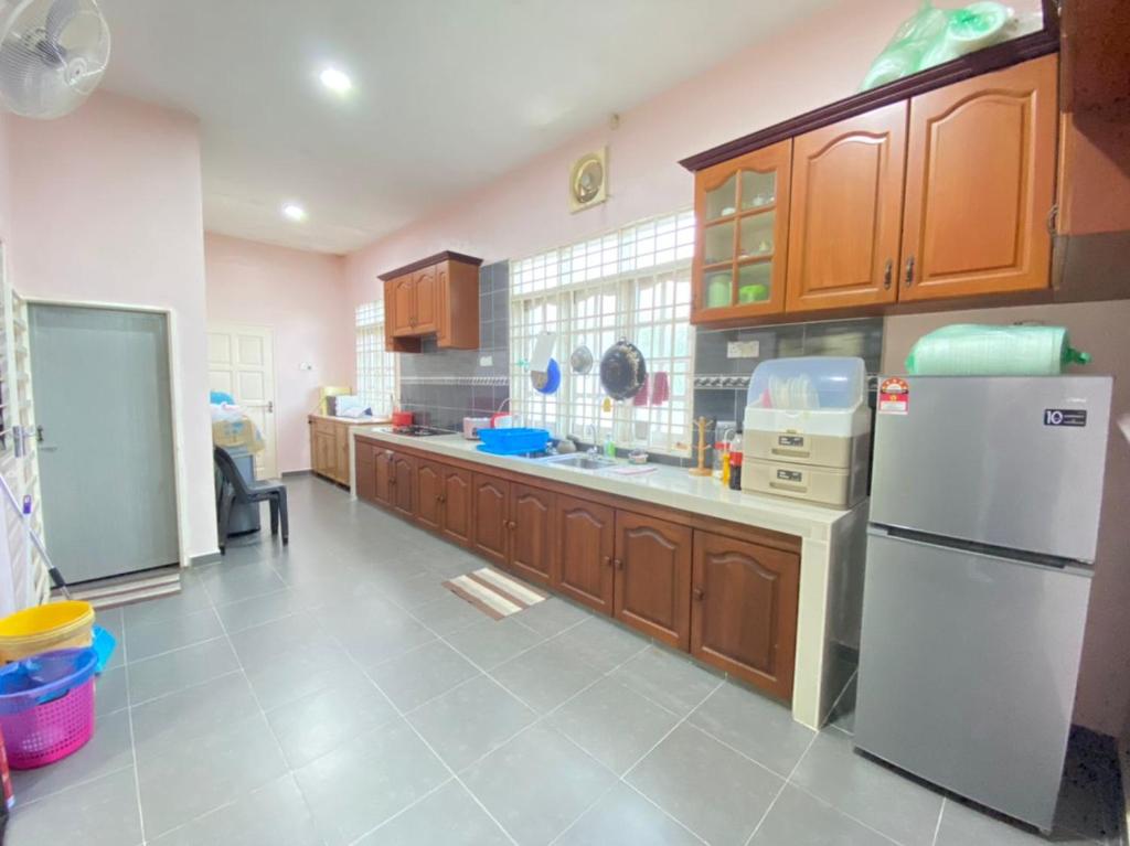 uma cozinha com armários de madeira e um frigorífico branco em Family Homestay em Kuala Terengganu