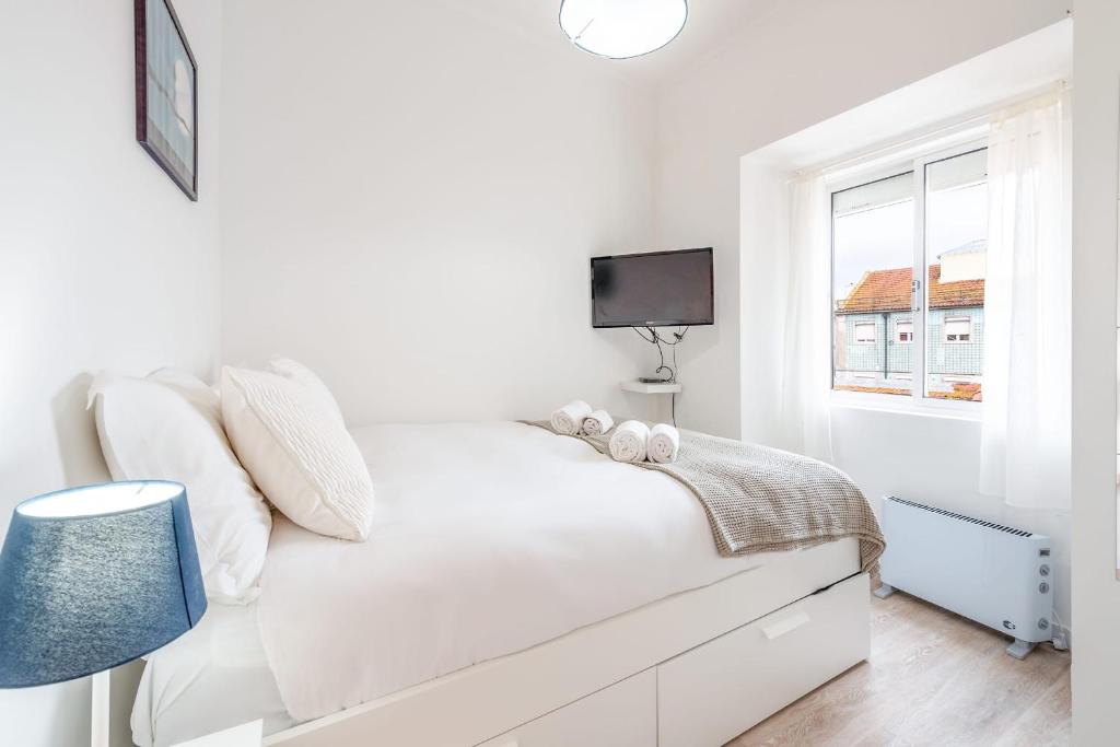 a white bedroom with a white bed and a window at GuestReady - Sweet Alcantara in Lisbon