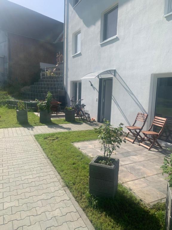 een patio met 2 stoelen en een huis bij Neue Ferienwohnung, Center Park, Bodensee, WAZ in Kißlegg