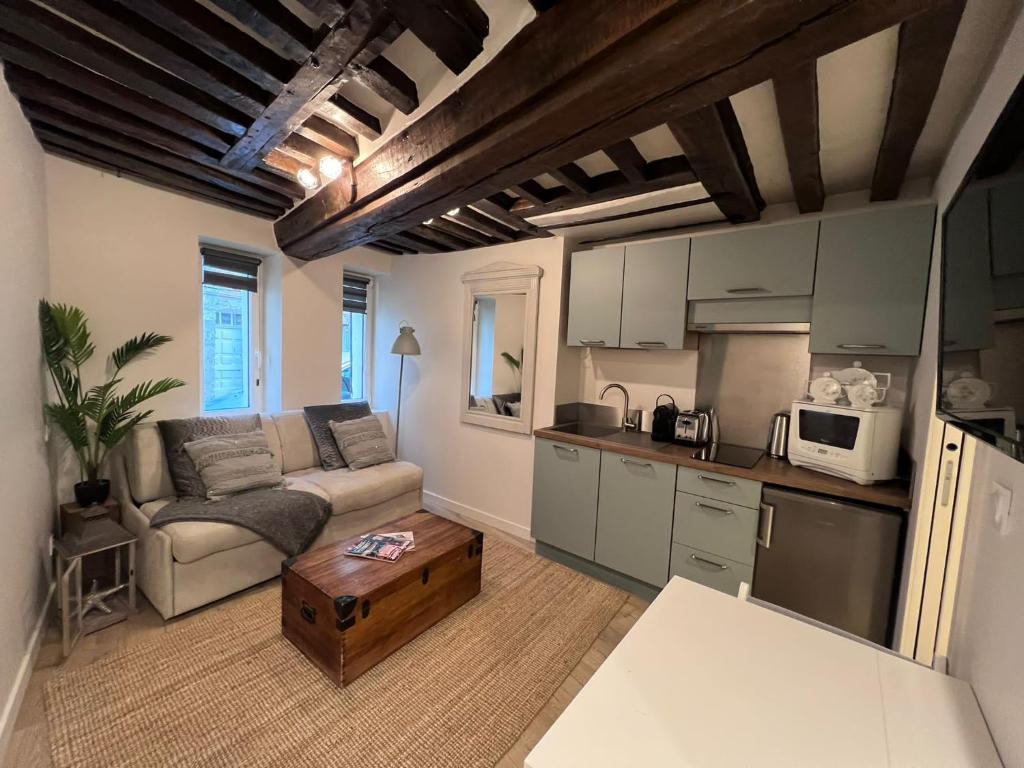 uma cozinha e uma sala de estar com um sofá e uma mesa em Les Maisons d'Augustine, nouvelle demeure de la cour Ste Catherine em Honfleur
