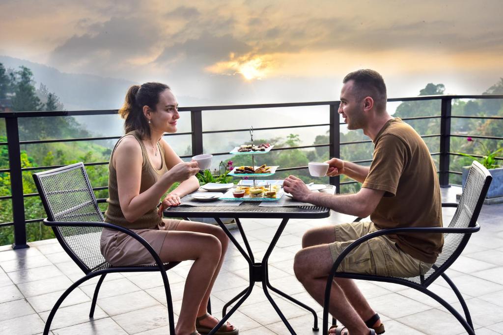 Um homem e uma mulher sentados à mesa com comida. em Pine Hill Residence em Kandy