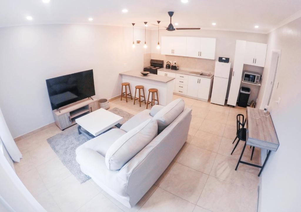 a living room with a white couch and a kitchen at Strelitzia Apartments in Westville