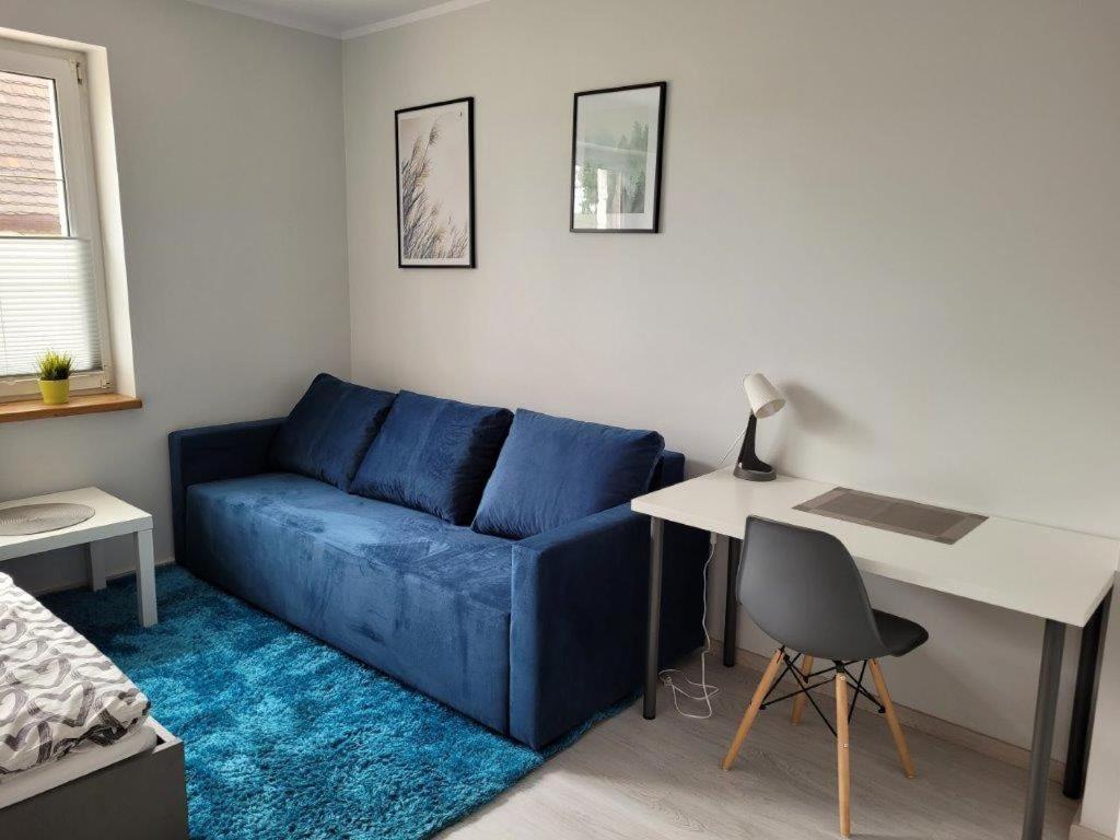 a living room with a blue couch and a desk at Apartamenty Promyk Wisełka in Wisełka
