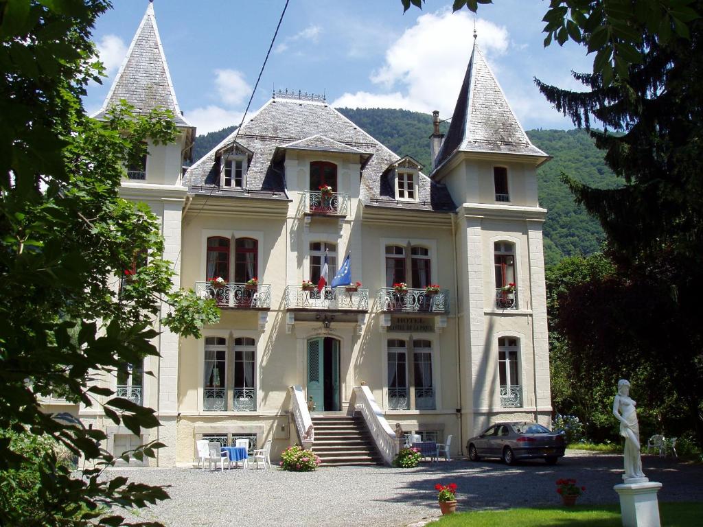 une grande maison blanche avec une voiture garée devant elle dans l'établissement Castel de la Pique, à Luchon