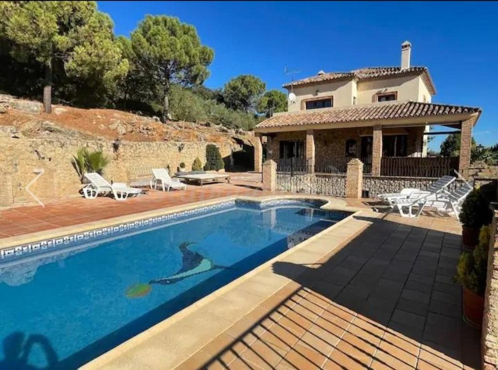a villa with a swimming pool in front of a house at El Molar in Ronda