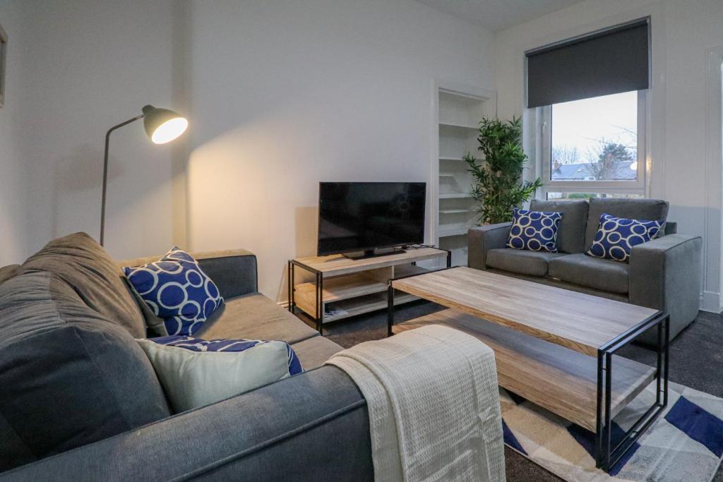 uma sala de estar com um sofá e uma televisão em Troon Golf Apartment em Troon