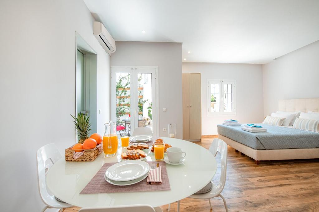 KORINA APART HOTEL KAVOS في كافوس: غرفة طعام بيضاء مع طاولة مع طعام وعصير برتقال