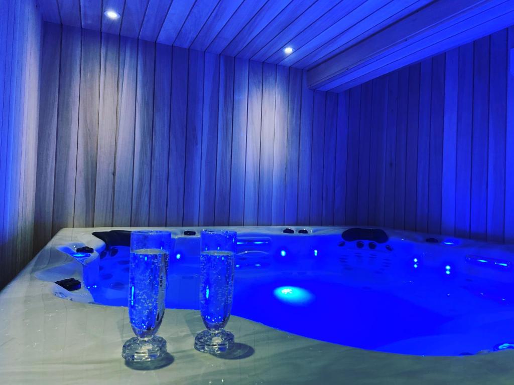 Habitación azul con bañera con 2 vasos sobre una mesa en Vieille rose, en Niort