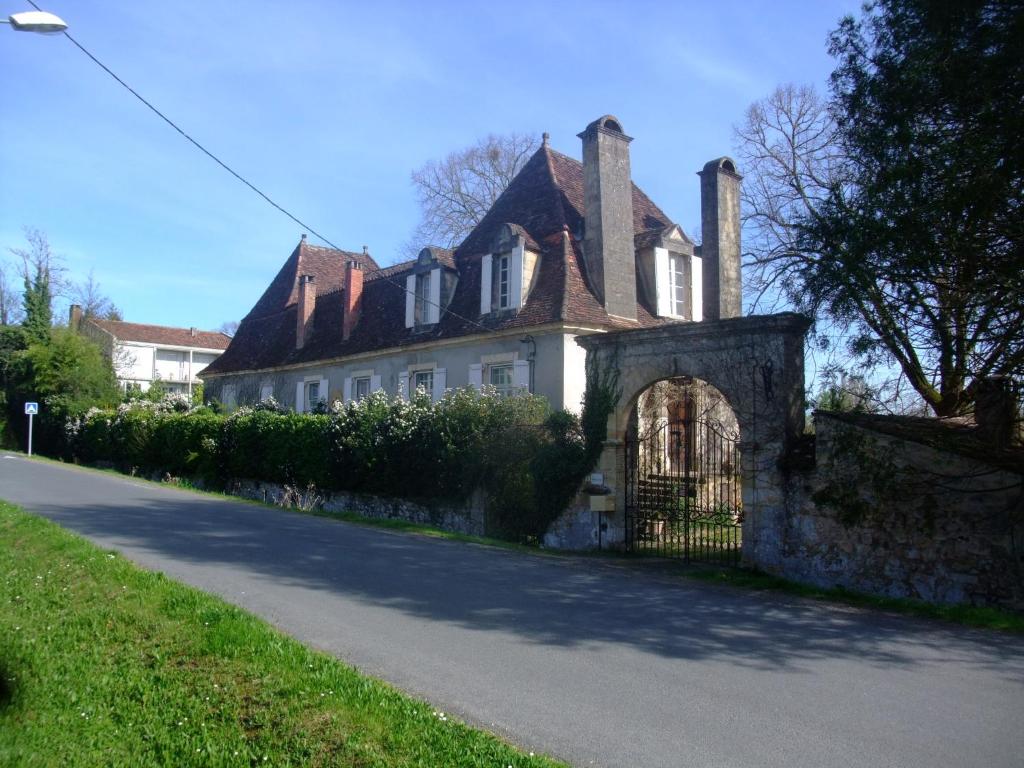 uma grande casa branca com um portão numa rua em LA GRANGE DES PÈRES - SÉJOURNEZ DANS UNE AUTHENTIQUE CHARTREUSE DU XVIIIème SIECLE em Saint-Cyprien