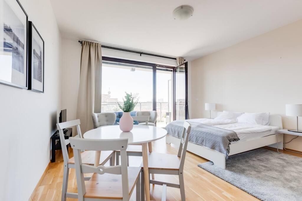 um quarto branco com uma cama, uma mesa e cadeiras em JT's Apartments Korunní str. em Praga
