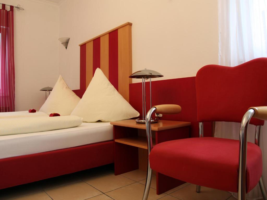 a hotel room with two beds and a red chair at Hotel Villa Casa in Düsseldorf