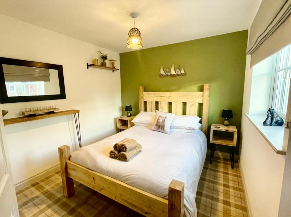 a bedroom with a large white bed with green walls at The Bay, Filey, Moonshine Cottage in Filey