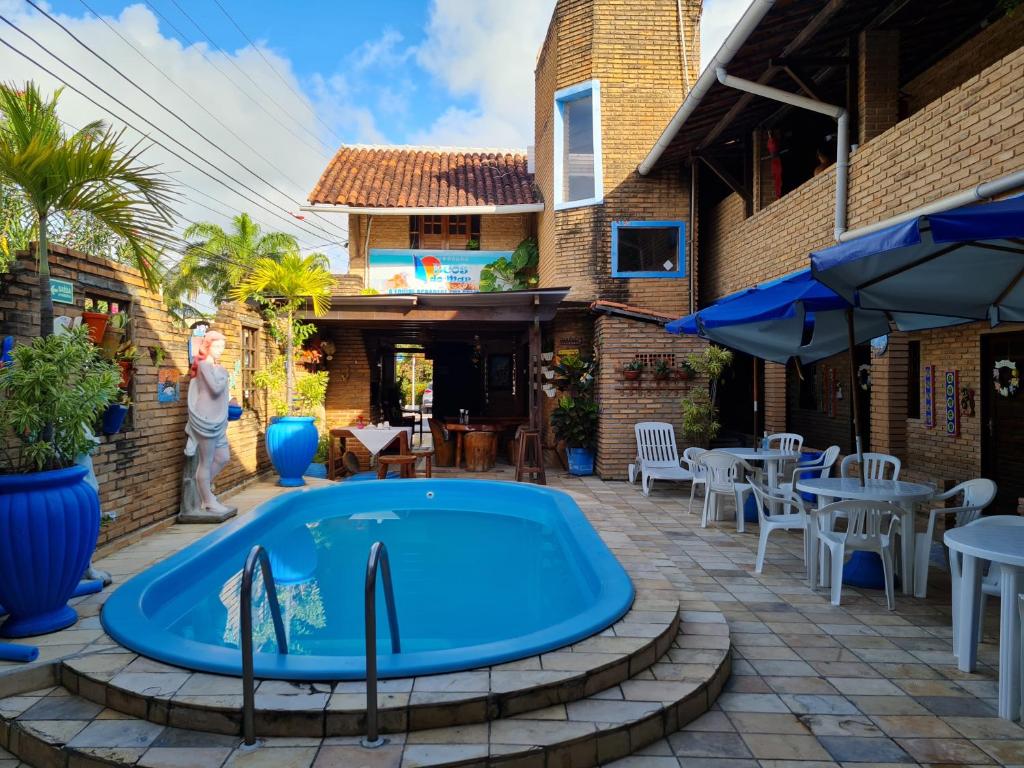 a pool in a patio with tables and umbrellas at Pousada Ecos do Mar in Praia do Frances