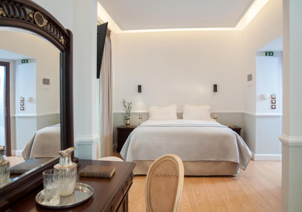 1 dormitorio con 1 cama grande y espejo en Acropolis Ami Boutique Hotel, en Atenas