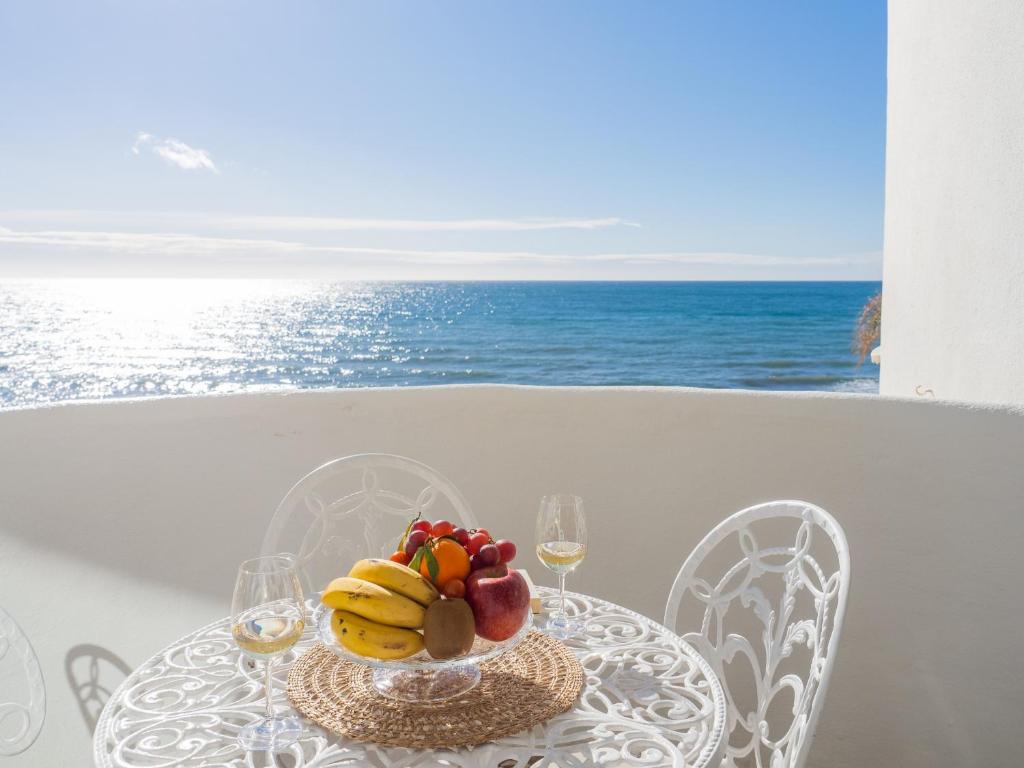 a table with a bowl of fruit and wine glasses at Cubo's La Bambera First Line Beach in Mijas Costa