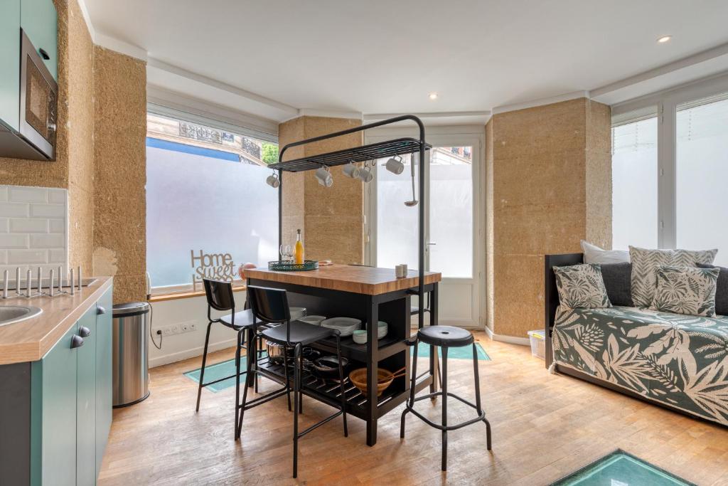 Les Vignes de Montmartre في باريس: مطبخ وغرفة معيشة مع طاولة وكراسي