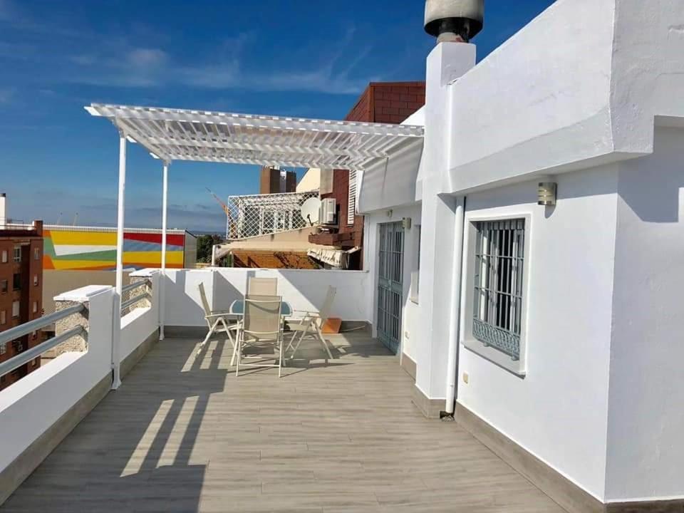 un balcone con sedie su un edificio bianco di Luxury Attics Avenida Italia PARKING INCLUIDO a Huelva