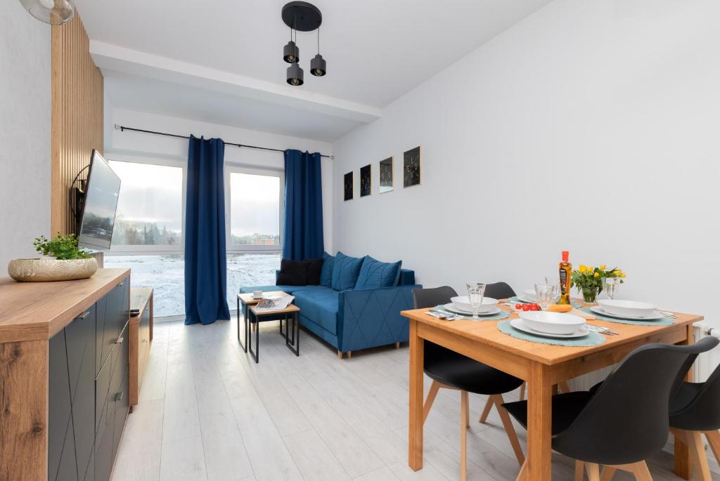 a living room with a table and a blue couch at Ostoya Pucka Apartament by Noclegi Renters in Puck