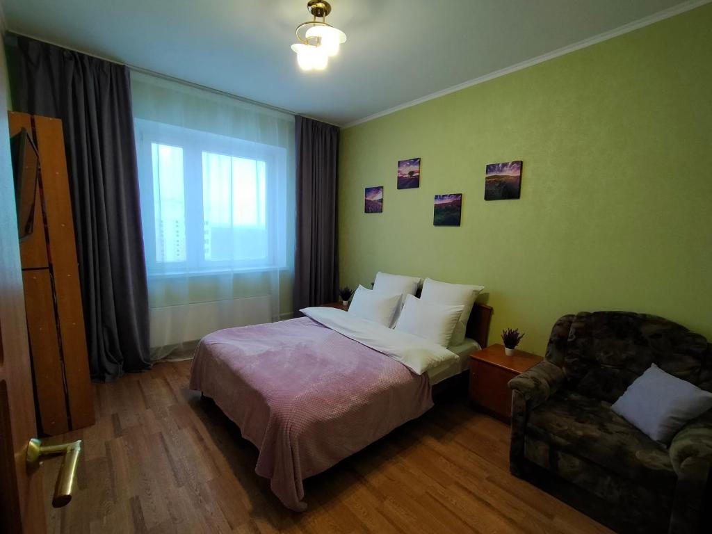 a bedroom with a bed and a chair and a window at ДЕНЬ И НОЧЬ Около горнолыжного комплекса in Kaluga