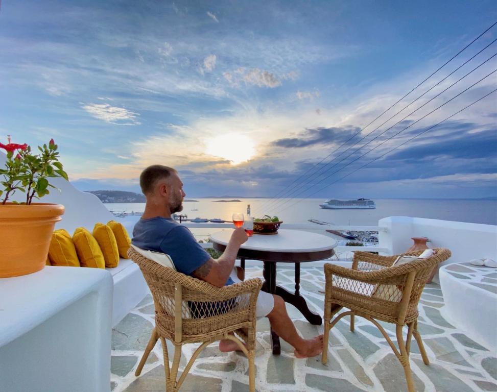 um homem sentado à mesa com um copo de vinho em Anemones Sea View em Míconos