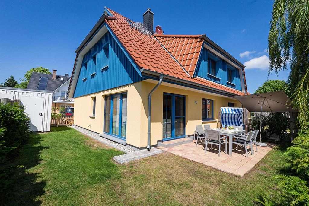 een blauw en geel huis met een tafel en stoelen bij Seemannsgarn in Zingst