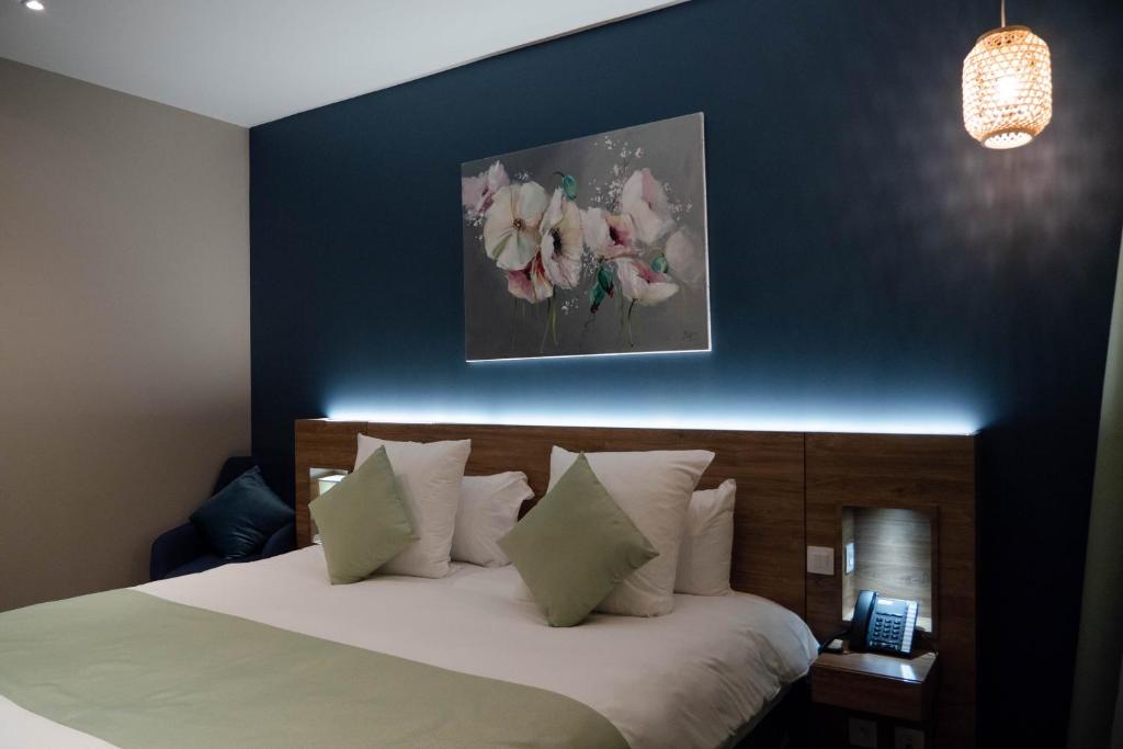 a bedroom with a bed with a blue wall at Hôtel & Restaurant La maison des blés in Boutervilliers