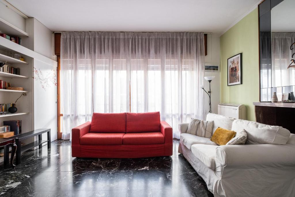 a living room with a red chair and a couch at Boldrini apartment with balcony by Wonderful Italy in Bologna