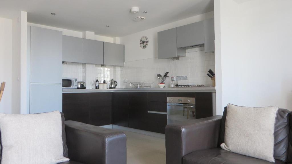 una cocina con armarios blancos y negros y 2 sillas en Citystay - The Vie en Cambridge