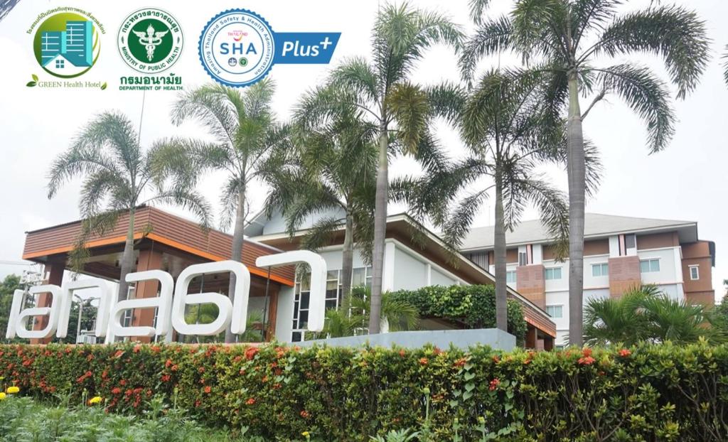 a building with palm trees in front of it at Akelada Hotel in Nang Rong