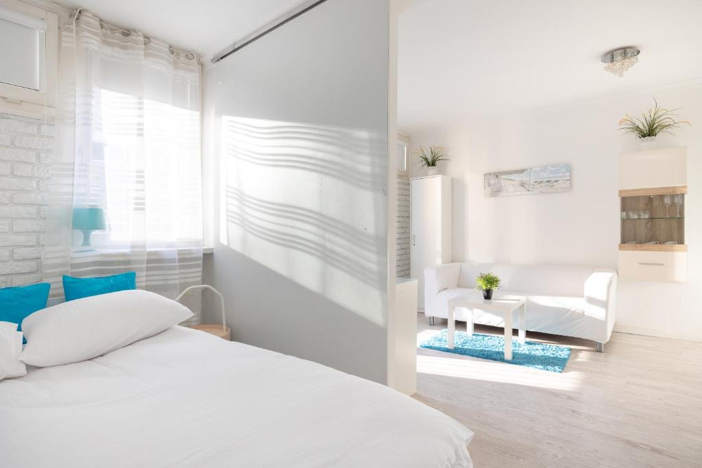 biała sypialnia z łóżkiem i krzesłem w obiekcie Rondo ONZ Business Apartment w Warszawie